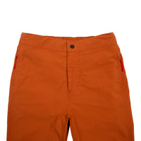 General front detail shot of Topo Designs Women's Lightweight Tech Pants in Brick orange showing waistband, fly, and zipper pulls on pockets.