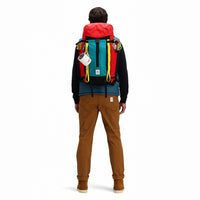 Model wearing Topo Designs Mountain Pack 28L hiking backpack with external laptop sleeve access in lightweight recycled "Red / Turquoise" nylon.