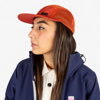 Model wearing Topo Designs Global mesh back Hat in "Clay" orange