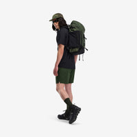 Model wearing Topo Designs Mountain Pack 28L hiking backpack with external laptop sleeve access in lightweight recycled "olive" green nylon.