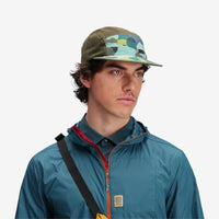 On model, front shot of Topo Designs Global mesh back Hat in "Green Camo" green. Unstructured 5-panel flexible brim packable hat.