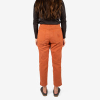 Back model shot of Topo Designs Women's Dirt Shirt & Pants in "Brick" orange.