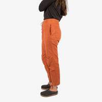 Side model shot of Topo Designs Women's Dirt Shirt & Pants in "Brick" orange.